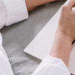 Пожилая женщина работает за компьютером с товарами для продажи на столе