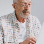 Пожилой человек за компьютером играет в цифровые игры